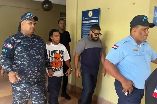 Agentes policiales conducen a un detenido esposado por el pasillo de un edificio judicial