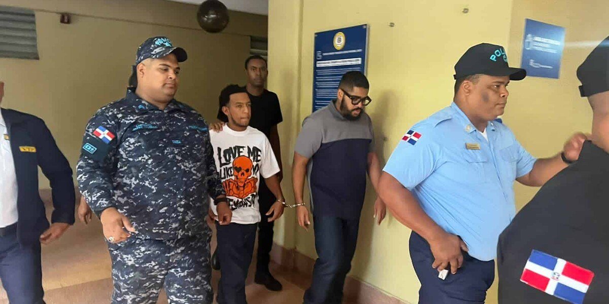 Agentes policiales conducen a un detenido esposado por el pasillo de un edificio judicial