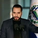 Nayib Bukele habla ante dos micrófonos en un atril, con banderas de El Salvador a ambos lados