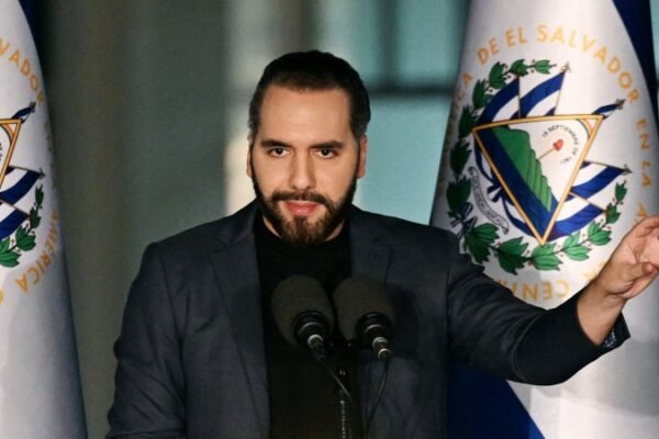 Nayib Bukele habla ante dos micrófonos en un atril, con banderas de El Salvador a ambos lados