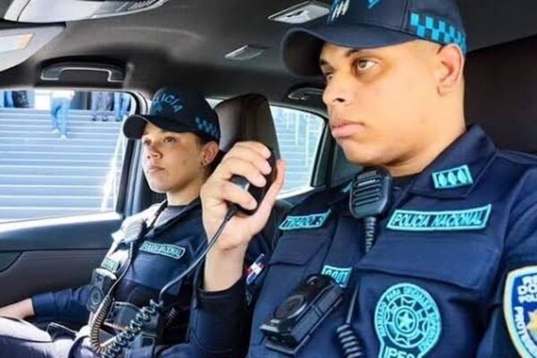 Dos agentes de la Policía Nacional dentro de una patrulla; uno habla por radio.