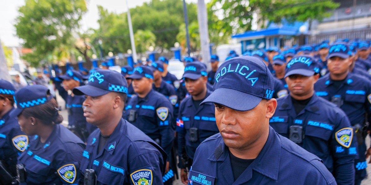 Agentes de la Policía Nacional con uniforme azul y gorras formados en fila.