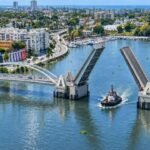 Puente basculante del Ozama: MOPC lo adjudica por RD$4,571 millones Representación del nuevo puente basculante sobre el río Ozama con sus dos tramos levantados para dar paso a un remolcador, con Santo Domingo al fondo
