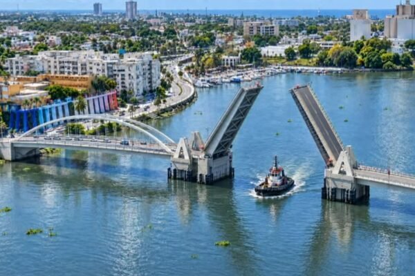 Representación del nuevo puente basculante sobre el río Ozama con sus dos tramos levantados para dar paso a un remolcador, con Santo Domingo al fondo