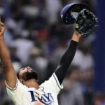 Un jugador de los Rays de Tampa Bay celebra con los brazos en alto, la gorra y el guante en una mano