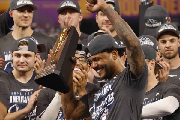 Jugadores de los Rays de Tampa Bay con gorras de la Serie Mundial celebran mientras uno de ellos alza el trofeo al Jugador Más Valioso de la Serie de Campeonato de la Liga Americana 2026
