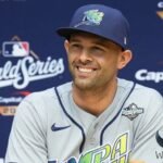 Un jugador con gorra y uniforme gris de los Rays de Tampa Bay sonríe durante una conferencia de prensa ante un fondo de la Serie Mundial 2026.