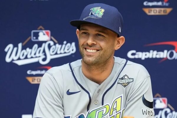 Un jugador con gorra y uniforme gris de los Rays de Tampa Bay sonríe durante una conferencia de prensa ante un fondo de la Serie Mundial 2026.