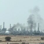 Columnas de humo negro se elevan sobre las chimeneas de una refinería en una zona desértica
