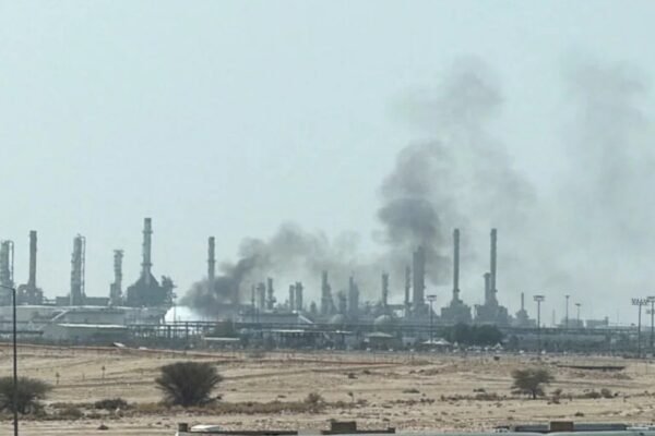 Columnas de humo negro se elevan sobre las chimeneas de una refinería en una zona desértica