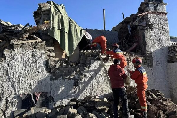 Bomberos con uniforme naranja trabajan sobre los escombros de una vivienda de piedra derrumbada, foto de archivo