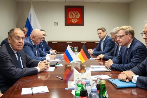 Las delegaciones de Rusia y Alemania, sentadas frente a frente en una mesa de reuniones con las banderas de ambos países y el escudo ruso al fondo