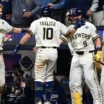 El jugador número 10 de los Cerveceros, Frelick, de espaldas, es recibido por sus compañeros con uniforme blanco frente al dugout