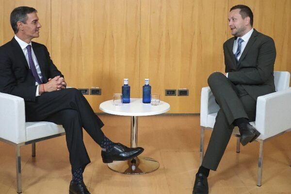 Pedro Sánchez y el primer ministro de Groenlandia, Jens-Frederik Nielsen, conversan sentados en dos butacas blancas separadas por una mesa baja