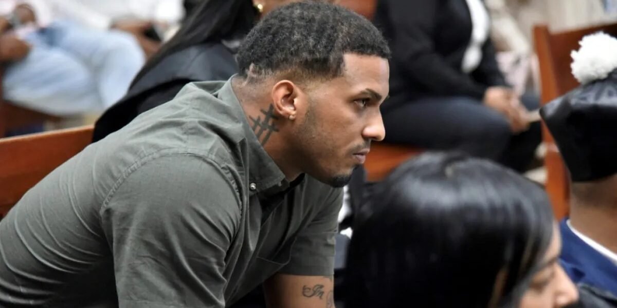 Wander Franco, con camisa verde oliva y un tatuaje en el cuello, sentado de perfil en un banco de madera de una sala de audiencias