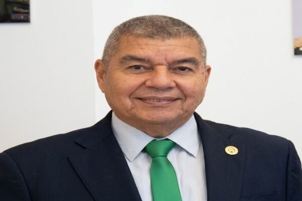 Wilmer Barrientos, de traje oscuro y corbata verde, sonríe en una sala de paredes blancas