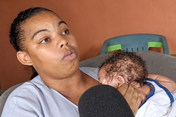 Yeraldin de la Paz habla ante un micrófono mientras sostiene a su bebé